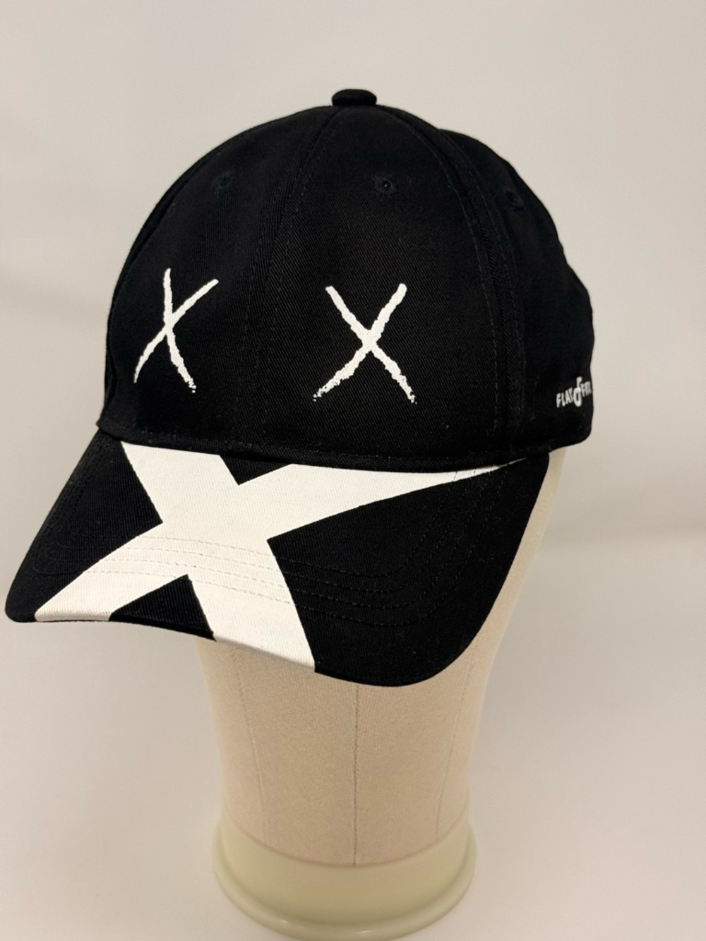 Black baseball cap with white embroidered "XX" eyes and a large white "X" logo